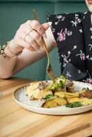 schließen oben von ein Gabel im ein Frau Hand Über ein Teller mit köstlich Essen im ein Restaurant foto