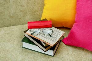 Zeitschrift mit Kreuzworträtsel, Bücher mit Brille auf ein Sofa mit bunt Kissen foto