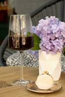 Makrone anf Kaffee im Weinglas auf ein hölzern Cafe Tabelle auf Blumen Hintergrund foto