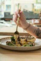 schließen oben von ein Gabel im ein Frau Hand Über ein Teller mit köstlich Essen im ein Restaurant foto