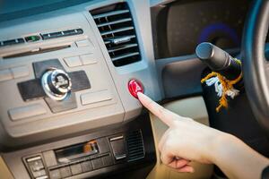 weiblich Hand drücken Notfall Licht Taste auf Auto Armaturenbrett. foto
