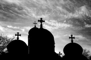 Silhouette von Kirche Kuppeln mit ein Kreuz beim Sonnenuntergang im schwarz und Weiß foto