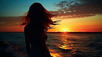 Mädchen s Silhouette gegen Meer und Sonnenuntergang foto