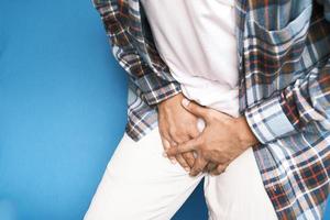 das Konzept des Prostata- und Blasenproblems, Schrittschmerzen eines jungen Menschen foto