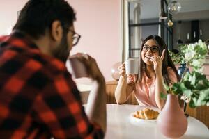 glücklich indisch Paar haben Frühstück und klein sich unterhalten zusammen im das Küche - - Freundschaft, Dating und Familie foto