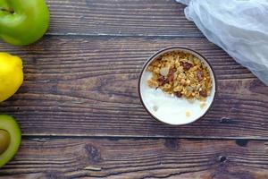 Joghurt-Müsli-Frühstück in Schüssel auf Holzuntergrund foto