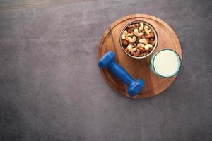 Draufsicht auf Glas Milch, Hantel und gemischte Nüsse im Glas auf schwarzem Hintergrund foto