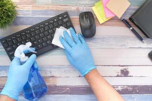 Geben Sie blaue Gummihandschuhe und die Tastatur zur Desinfektion des weißen Gewebes ein foto