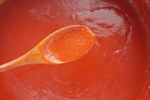 Tomatensauce in einem kleinen Glas mit frischen Tomaten auf dem Tisch foto