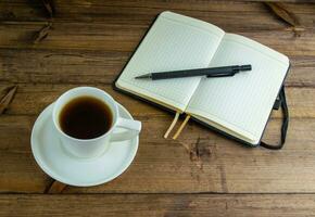 Kaffee im ein Tasse, Notizbuch und Stift. foto