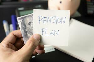 Papier Hinweis mit Text die Pension planen mit Schreibwaren und Dollar auf Schreibtisch. die Pension planen. Pensionierung Konzept. die Pension Berechnung Konzept. foto