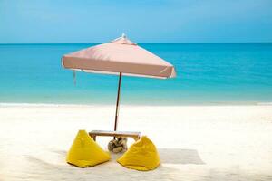 schön Aussicht von tropisch Strand, Thailand. Gelb Strand Bett, Bohne Tasche Stuhl und Regenschirm auf Weiß Sand zum entspannend suchen aus Über das Blau Meer Ozean. sich ausruhen im das Urlaub Konzept. foto