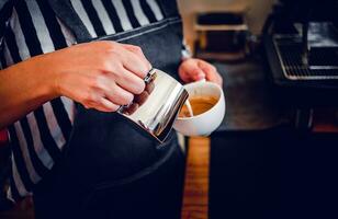 Fachmann Barista im Kaffee Geschäft Herstellung Gießen gedämpft Milch in das Kaffee Tasse Herstellung Latté Speisekarte foto