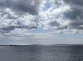 Ladung Schiff im das öffnen Meer. Weiß Wolken Über ein stürmisch Himmel Hintergrund und Meer foto