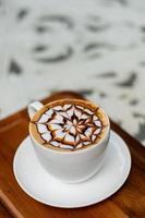 Heißer Latte-Art-Kaffee auf Holztisch, Zeit zum Entspannen? foto