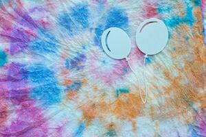 ein Paar von Weiß Luftballons auf ein bunt Krawatte Farbstoff Stoff foto
