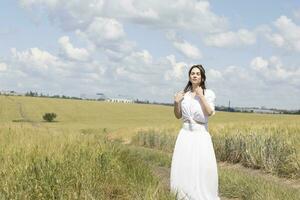 ein Frau im ein Weiß Kleid Stehen im ein Feld foto