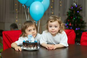 zwei Kinder Sitzung beim ein Tabelle mit ein Kuchen foto