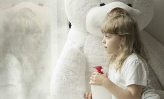 ein wenig Mädchen Sitzung auf ein Couch mit ein Weiß Teddy Bär foto