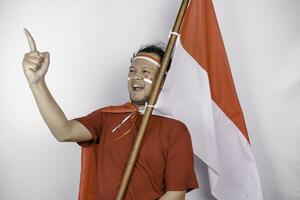 ein erleuchten jung asiatisch Mann ist tragen rot T-Shirt und halten Indonesiens Flagge sieht aus inspiriert durch Ideen, isoliert durch Weiß Hintergrund foto