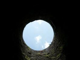 Stein Gut Loch, alt Konstruktion von innen, Backstein Wände und Blau Himmel Hintergrund, fallen Nieder im das Gut Konzept foto