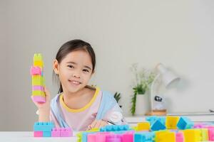 wenig Mädchen ist glücklich spielen bunt Block Rätsel. im das Weiß Zimmer foto