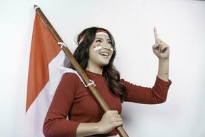 aufgeregt jung asiatisch Frau feiern indonesisch Unabhängigkeit Tag halten das indonesisch Flagge isoliert auf Weiß Hintergrund foto