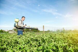 ein Farmer mit ein Pestizid Sprühgerät Maschine Spaziergänge über das Feld. Schutz von Pflanzen von Insekten und Pilz- Infektionen. chemisch Industrie im Landwirtschaft Landwirtschaft. Widerstand von das Ernte zu Schädlinge. foto