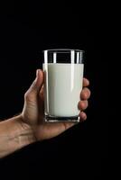 Hand halten ein Glas von frisch Milch isoliert auf schwarz Hintergrund. ai generiert foto