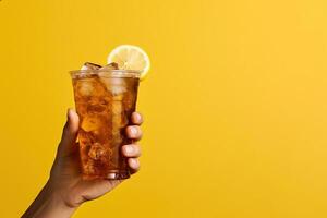 ein Hand halten wegbringen Plastik Tasse von köstlich vereist Zitrone Tee isoliert auf Gelb Hintergrund mit Kopieren Raum. ai generiert foto
