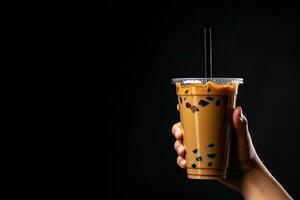 ein Hand halten wegbringen Plastik Tasse von köstlich vereist Blase Milch Tee und schwarz Perlen isoliert auf schwarz Hintergrund mit Kopieren Raum. ai generiert foto