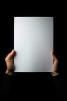 ein Mensch Hand halten ein leer Blatt von Weiß Papier oder Karte isoliert auf schwarz Hintergrund. ai generiert foto
