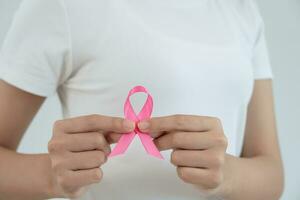 Frau hält Brustkrebsbewusstsein mit rosa Schleife. weibliches gesundheitscheckbewusstsein. Internationaler Frauentag und Weltkrebstag. zeichen krebs, symbolisch, gesundheitsversorgung, unterstützung von patienten, rechtzeitige diagnose foto