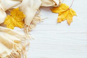 Blätter im Herbst mit einem Schal auf einem hölzernen Hintergrund mit Kopierraum foto