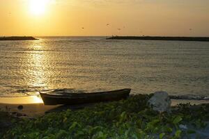 Kanu auf das Sand Nächster zu das Meer beim Sonnenuntergang. Sonnenuntergang im Cartagena de Indien foto
