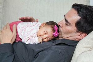 Porträt von jung Vater beim Zuhause mit seine einer Monat Baby Mädchen. Vaterschaft Konzept. Familie Liebe Konzept. foto