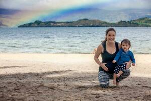 jung schwanger Frau haben Spaß mit ihr Baby Mädchen beim das schön Weiß Strand von See insgesamt gelegen im das Abteilung von Boyaca beim 3.015 Meter über Meer Niveau im Kolumbien foto