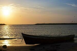 Kanu auf das Sand Nächster zu das Meer beim Sonnenuntergang. Sonnenuntergang im Cartagena de Indien foto