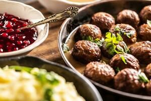 Schwedisch Essen kottbullar Fleischklößchen, serviert im ein schwenken mit püriert Kartoffeln, Petersilie und Cranberry Soße foto