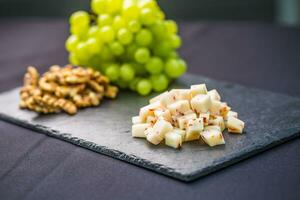 Käse Stücke saftig Trauben und Walnüsse auf Schiefer Tafel foto