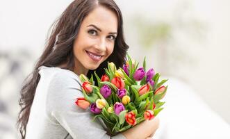 glücklich dunkel behaart Frau halten ein schön Strauß voll von Tulpen während National Damen Tag foto
