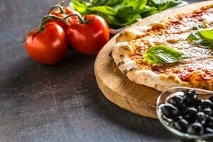 Italienisch traditionell Pizza Margarita auf runden hölzern Tafel mit Basilikum Tomaten und Parmesan foto