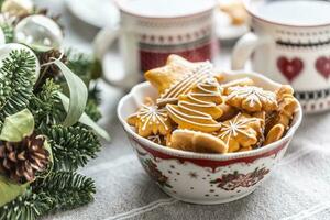 ein Schüssel voll von Weihnachten Lebkuchen auf das Tabelle LED ein Advent Kranz und zwei Tassen mit Kaffee, schlagen oder Tee foto