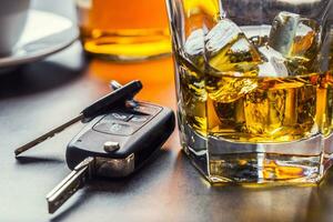 Auto Schlüssel und Glas von Alkohol auf Tisch. foto