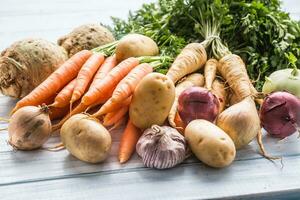 Sortiment von frisch Gemüse auf hölzern Tisch. Karotte Pastinake Knoblauch Sellerie Zwiebel und Kohlrabi foto