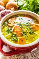 Hähnchen Suppe Brühe im ein Jahrgang Schüssel mit hausgemacht Nudeln Karotte Zwiebel Sellerie Kräuter Knoblauch und frisch Gemüse foto
