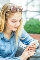 Mädchen SMS auf das Clever Telefon im ein versand Einkaufszentrum Sitzung im Internet kostenlos Zone foto