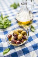 Grün und rot Oliven im Schüssel mit Olive Öl und Karaffe im das Hintergrund foto