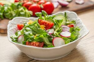 frisch Frühling Salat mit Grün Blätter Tomaten Ei Rettich rot Zwiebel jung Erbsen Prosciutto Feta Käse und Olive Öl foto