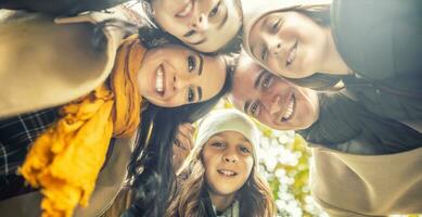 Foto von unten auf ein glücklich Familie mit drei Kinder lächelnd, Putten ihr Köpfe zusammen